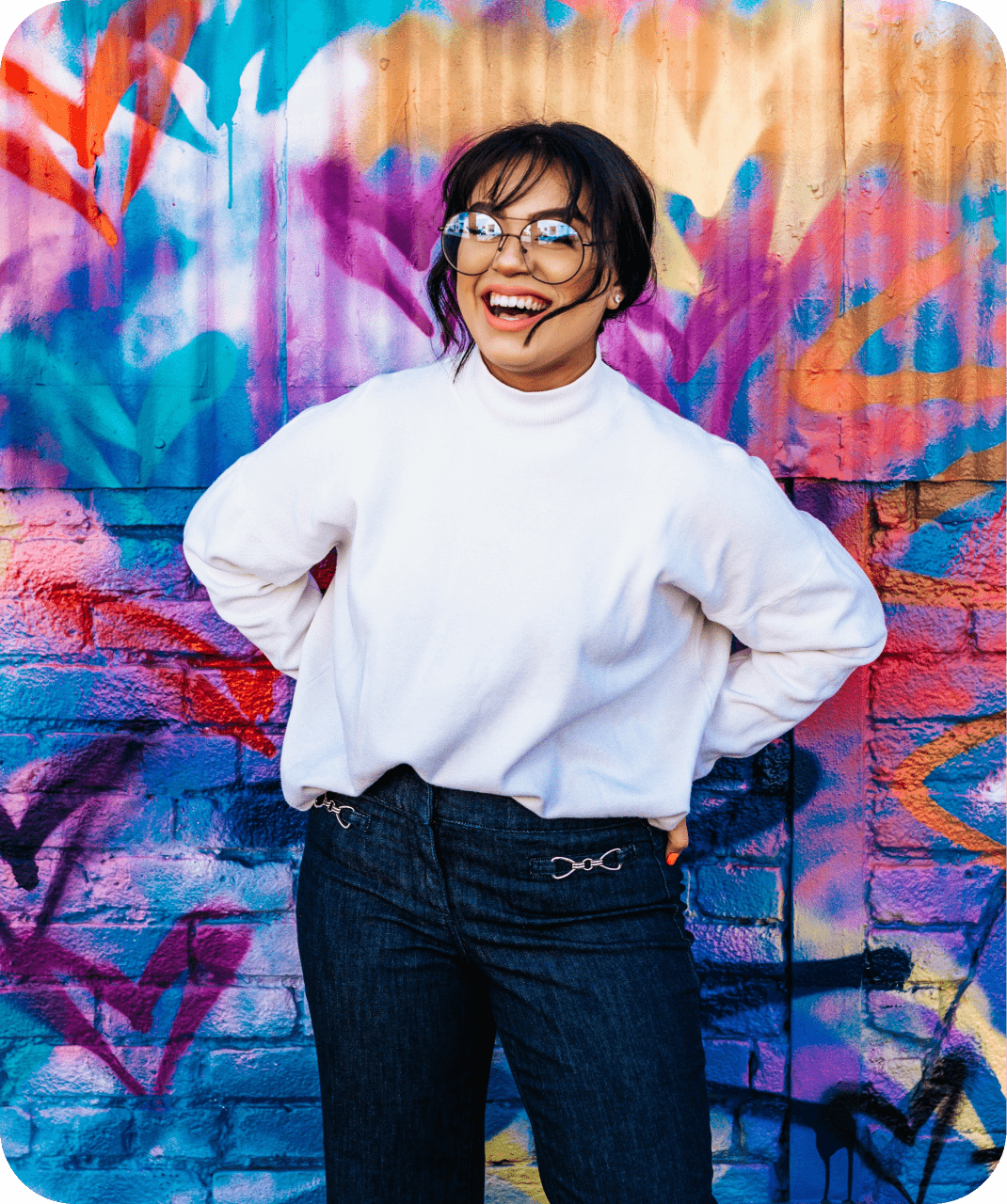 a girl in white shirt and blue jeans with a smile on her face wearing glasses